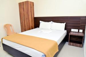ein Schlafzimmer mit einem großen Bett mit hölzernem Kopfteil in der Unterkunft Hotel Devis Velankanni in Velankanni