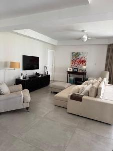a living room with two couches and a flat screen tv at Guarajuba com 5 suítes, piscina e espaço gourmet in Camacari