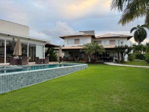 a house with a swimming pool and a yard at Guarajuba com 5 suítes, piscina e espaço gourmet in Camacari