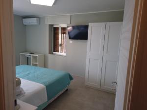 a small bedroom with a bed and a television at La Casa del Principe in Alì