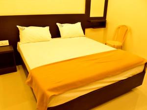 ein Schlafzimmer mit einem großen Bett und einer orangefarbenen Decke in der Unterkunft Hotel Devis Velankanni in Velankanni + 3 Fotos
