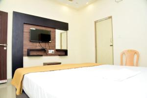 ein Schlafzimmer mit einem Bett und einem Fernseher an der Wand in der Unterkunft Hotel Devis Velankanni in Velankanni