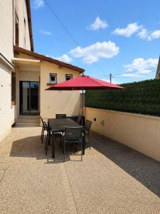 a black table with a red umbrella on a patio at Résidence d'Emilie in Luxeuil-les-Bains +6 photos