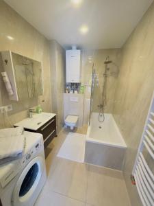 a bathroom with a tub and a sink and a washing machine at Apartament Maja 10-3 in Nowy Sącz