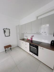 a kitchen with white cabinets and a black oven at Apartament Maja 10-3 in Nowy Sącz