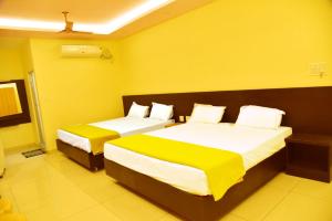 zwei Betten in einem Zimmer mit gelben Wänden in der Unterkunft Hotel Devis Velankanni in Velankanni