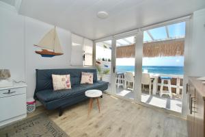 a living room with a blue couch and a view of the ocean at Seaside Beach Chalet in Anfeh PEARL in Anfah