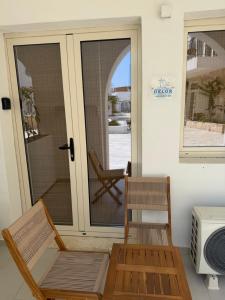 a porch with two chairs and a glass door at Delor Studio Drymades,Santorini in Dhërmi