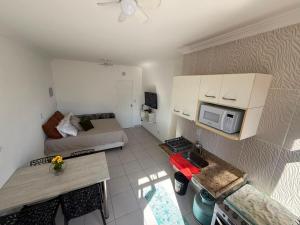 a small living room with a bed and a microwave at Studio 1202 Confortável, Piscina e próximo a praia! in Guarujá