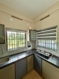 a large kitchen with a counter top and two windows at Fruits Garden Resort in Kotamangalam +9 photos