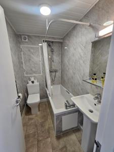 a bathroom with a tub and a sink and a toilet at Beau Rivage in St. Brelade +44 photos