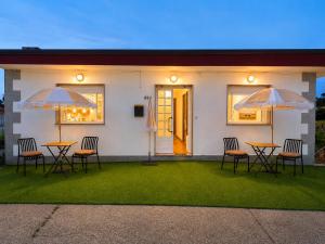 a house with two tables and chairs and two umbrellas at Soutullo Praia in Sanxenxo