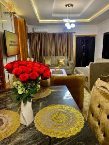 a living room with a table with a vase of red roses at Derucci Luxury Apartment in Owerri
