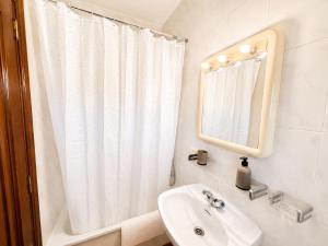 a white bathroom with a sink and a mirror at Soutullo Praia in Sanxenxo +8 photos