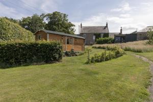 a wooden cabin in a yard next to a house at Teasel Shepherd's Hut in Berwick-Upon-Tweed