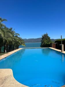 a large swimming pool next to a body of water at Casa Lago Colbun in Talca