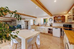 a large kitchen with a white table and chairs at Longère Colpernou in Plouguernével