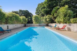 a swimming pool with two chairs and a swimming pool at Longère Colpernou in Plouguernével