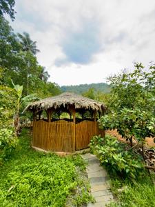 a wooden gazebo with a straw roof at Fruits Garden Resort in Kotamangalam