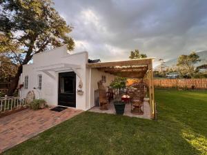 a white house with a pergola and a yard at Greyton Cottage in Greyton