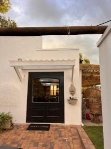 a black door on a white house with a patio at Greyton Cottage in Greyton +14 photos