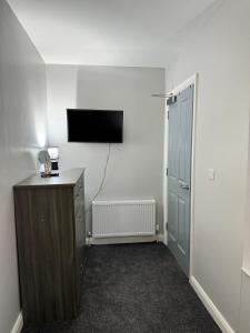 a room with a tv and a dresser and a door at Ogle Street 1-Bed Apartment in Armagh