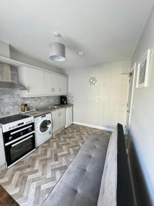a kitchen with white cabinets and a washer and dryer at Ogle Street 1-Bed Apartment in Armagh +3 photos