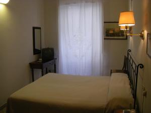 a bedroom with a bed and a window with a white curtain at Albergo Cannon d'Oro in Siena