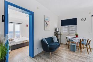 a room with a blue chair and a table and a bed at Apartments Joy in Cavtat