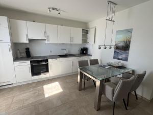 a kitchen with white cabinets and a table and chairs at Sonnengarten 19 in Kellenhusen