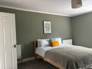 a bedroom with a bed with gray walls and orange pillows at Delightful Durham Home in Gilesgate
