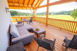 a porch with a couch and chairs on a wooden deck at Hans-Girgl-Hof in Langdorf