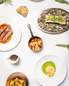 a table with plates of food and bowls of food at Au Coin Du Feu in Megève