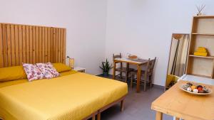 a bedroom with a yellow bed and a table at B&B BELLAMI' in Tuglie