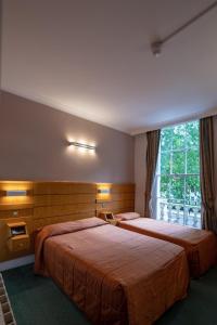 two beds in a hotel room with a window at The Nayland Hotel in London