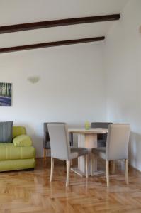 a dining room with a table and chairs and a couch at Holiday Home Archipelago in Lovran