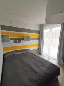 a bedroom with a bed and a striped wall at Ludna 27 in Niechorze
