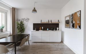 a kitchen with white cabinets and a black table at Limehome Chemnitz Hartmannstraße in Chemnitz