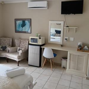 a room with a desk with a microwave and a couch at Sunbirds Bed & Breakfast in Southbroom