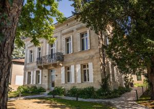 an old stone house with a balcony and trees at La Villa des Vignes in Saint-Émilion
