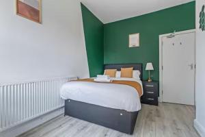 a bedroom with a bed with a green wall at Coventry Contractor Hub - 4-Bedroom House with Free Parking-CV5 in Spon End