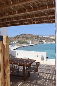 a table and chairs on a deck with a view of the ocean at Almira Prassa Beach House Kimolos in Prasonísi