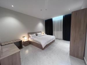 a bedroom with a bed and a desk in a room at البساتين بارك للشقق المخدومه in Al Baha