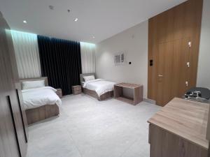 a hotel room with two beds and a desk at البساتين بارك للشقق المخدومه in Al Baha