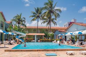 a pool at a resort with people sitting in chairs at Hotel Parque das Aguas in Aracaju