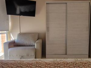a bedroom with a chair and a sliding door at Lucipri CyN in Arroyito