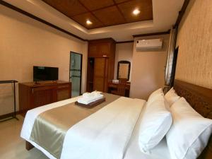 a bedroom with a bed with white sheets and a television at Fueangfu Pool Villa Chaweng in Chaweng