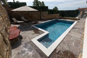a swimming pool in a yard with a stone wall at Vila Mira in Gračišče