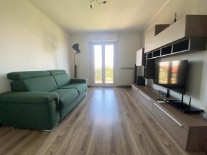 a living room with a green couch and a television at Malpensa-Milano, Terrazza, 2 Bagni in Galliate
