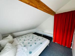 a small bedroom with a bed with a red curtain at Ferienwohnung Munchen in Vaterstetten